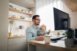 father working remote with baby in lap