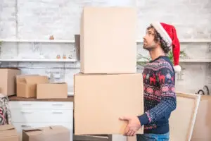 man with christmas outfit holding moving boxes