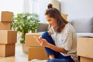 woman calling moving company with boxes behind her