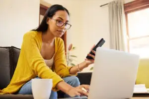 woman researching on laptop and phone
