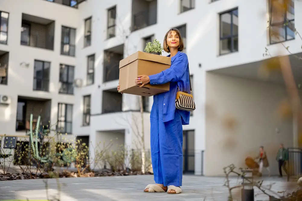 woman with moving box outside apartment