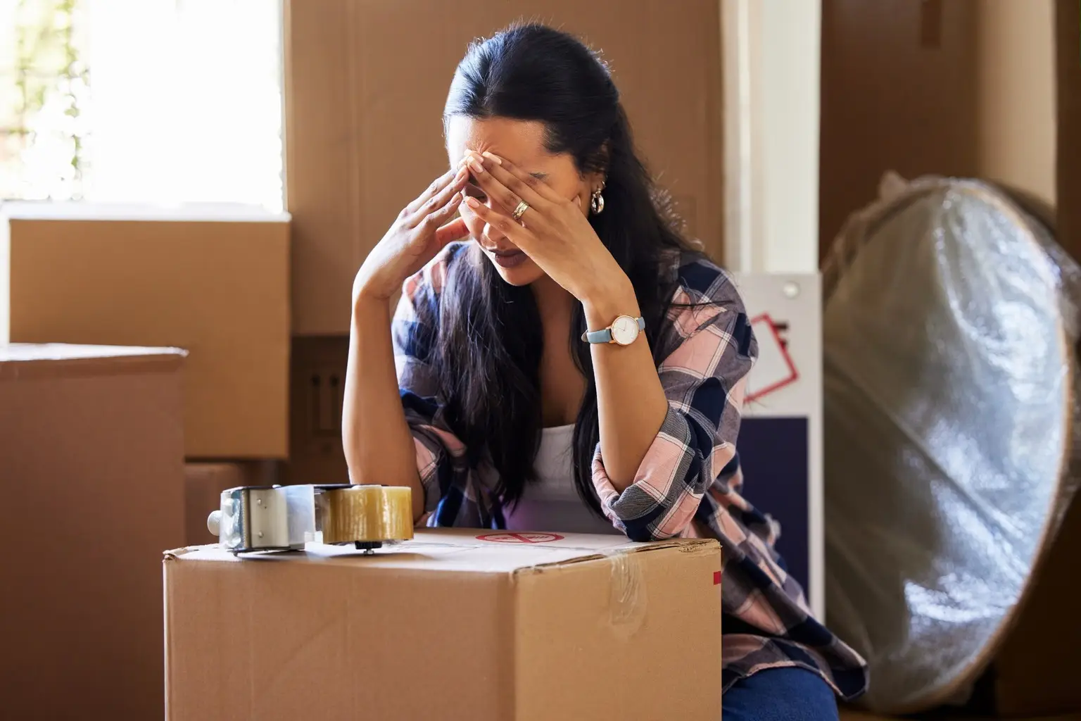 Person sitting among packed boxes during a difficult move